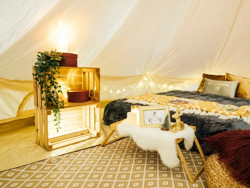 Inside a furnished tent: a made bed, rugs and warm lights